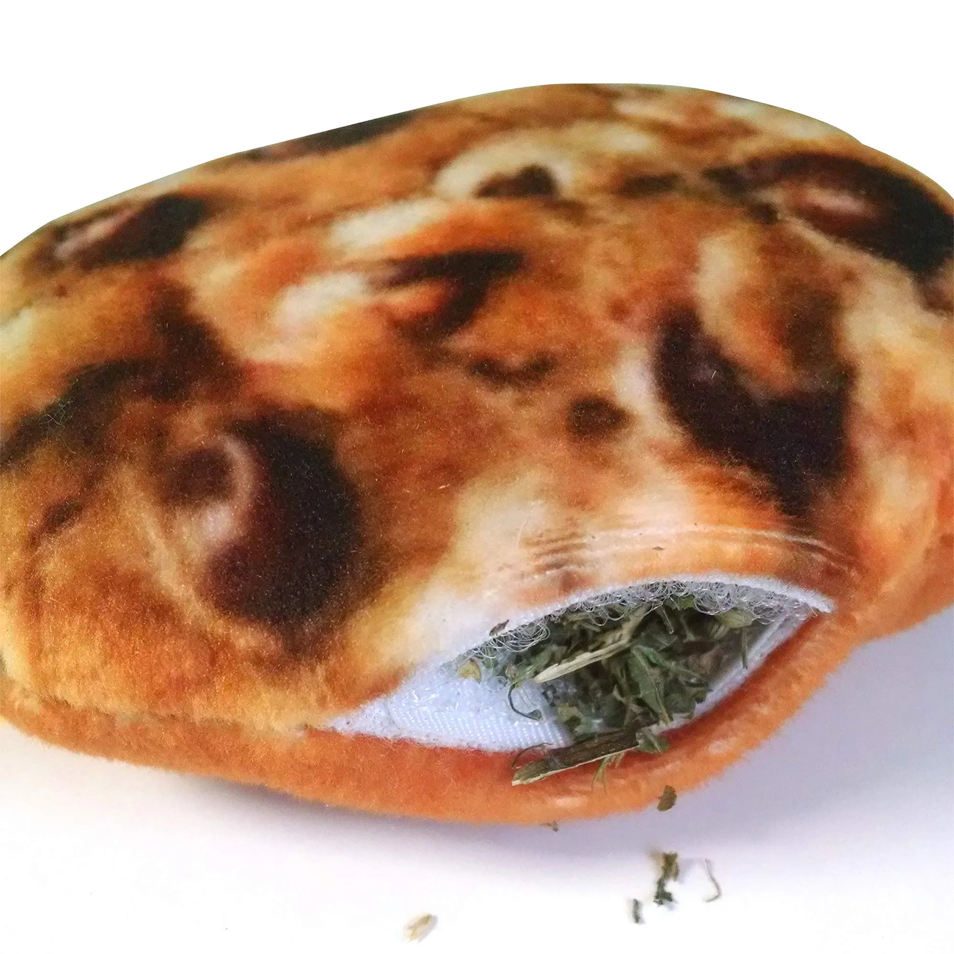 Close-up of the refillable catnip pocket in the Meowijuana cookie toy, slightly filled with loose catnip.
