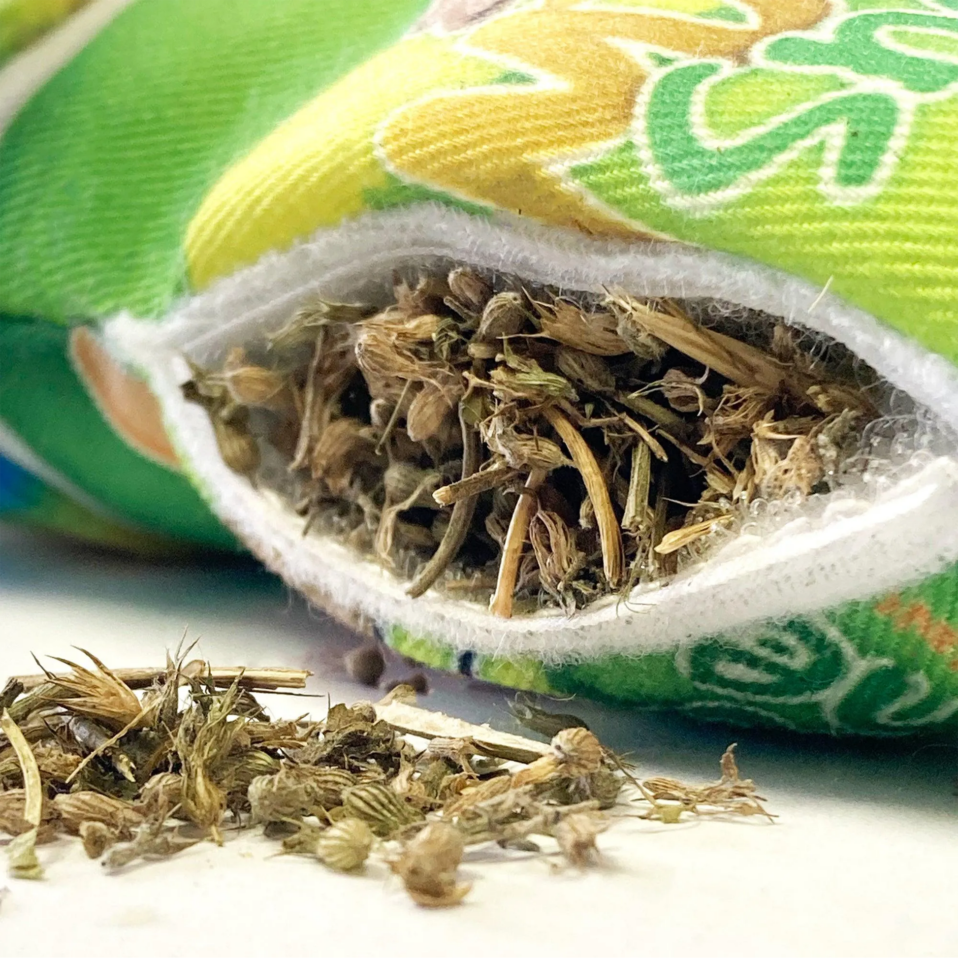 Close-up of the refillable pocket on the snow cone toy, showing loose premium catnip spilling out.